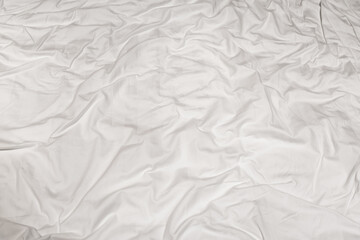Close-up of the texture of a crumpled white sheet with tinted folded lines