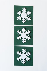 three white foam snowflakes on dark green paper tiles