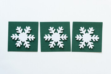 three white foam snowflakes on dark green paper tiles