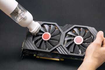 The master performs maintenance of a modern video card, cleaning the video card with a vacuum...