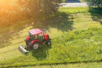 Fototapeta premium Tractor mows the grass in the yard of the house