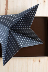 folded paper with dot pattern inside a cardboard box on a wooden surface