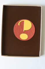 question mark on a circle inside a plain cardboard box with dark brown paper liner