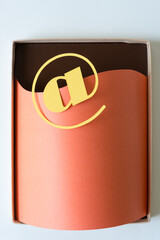 at sign and nothing - paper shape on blank paper tucked inside a cardboard box