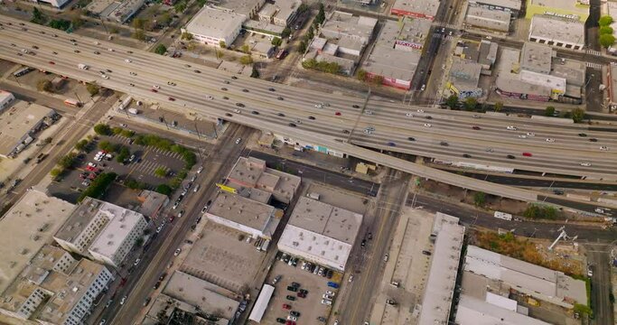 Traffic on the roads of Los Angeles at sunny daytime. Drone footage over the low buildings of the metropolis in United States. Top view.