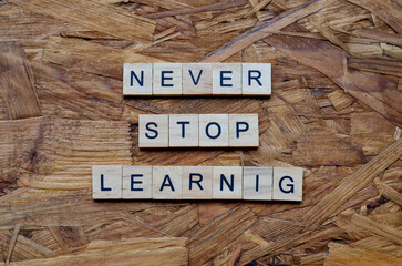 Never stop learning text on wooden square, motivation and inspiration quotes
