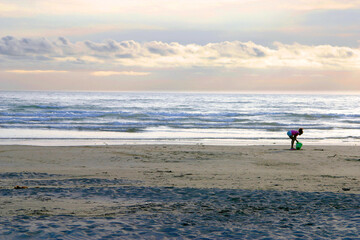 Young Girl Plays on the Beach by the Vast Gray Sea