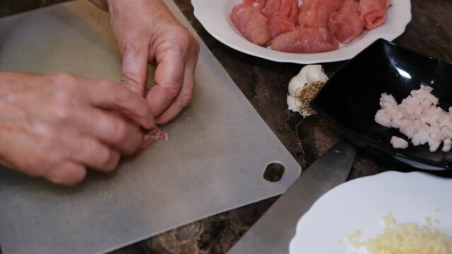 A delicious dish of pork mince wrapped with delicious pieces of bacon. Preparation of chevapchichi. Woman hands cooking meat rolls