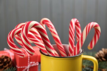 Many sweet candy canes in cup on grey background, closeup. Traditional Christmas treat