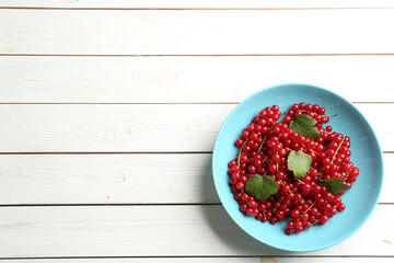 Naklejka na ściany i meble Delicious red currants and leaves on white wooden table, top view. Space for text