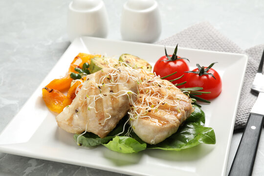Tasty grilled fish served on light grey marble table