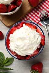 Delicious strawberries with whipped cream served on wooden table, flat lay