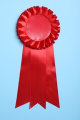 Red award ribbon on turquoise background, top view