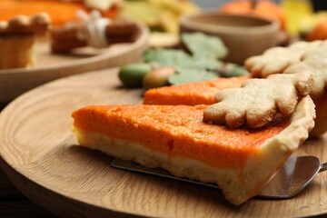 Slices of delicious homemade pumpkin pie on wooden plate, closeup