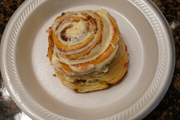 Cinnamon roll on a styrofoam plate.
