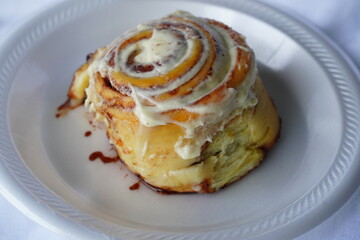 Cinnamon roll on a styrofoam plate.