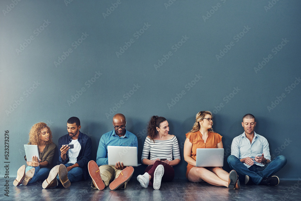 Aufkleber diverse digital team exploring online platform on many devices, sitting against copy space together.