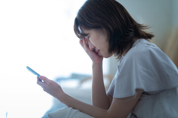 スマートフォンを手に悩む女性