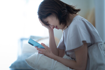 スマートフォンを手に悩む女性