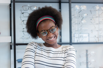 close up, portrait young woman African american afro hair smile wear spectacles standing at optical shop. modern ophthalmologist concept.
