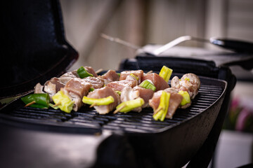 Raw pork meat skewers just placed on a barbecue garnished with mushrooms and green peppers