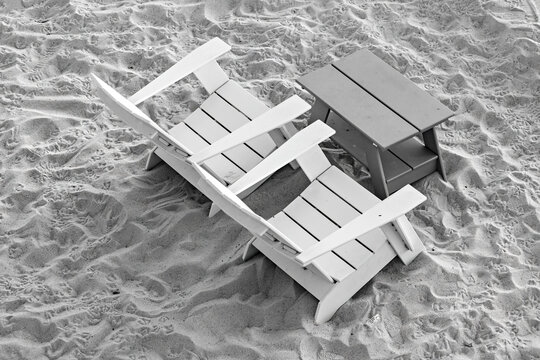 Beach wooden table and chairs on the sand top view, black and white photo
