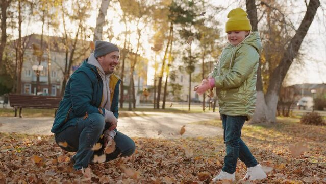 happy dad child girl throw up dry yellow leaves park. happy family playing game of autumn golden leaves. chidhood dream. fun together with dad nature. leaves fly up high rising. teamwork happy family.