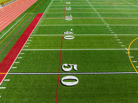 Aerial image of a typical synthetic turf football field 50 yard line in white. 	