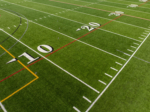 Aerial image of a typical synthetic turf football field 10 yard line in white. 	