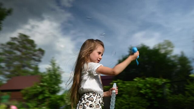 Little girl plays with soap bubbles outdoors. Video 360 degrees.