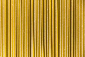 Obraz premium Italian healthy food background, raw spinach spaghetti filling the frame in a textured design of green vertical pasta lines.