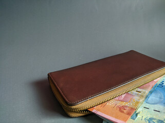 Brown wallet with some money isolated over gray background