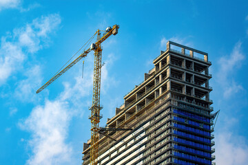 Crane and building site under construction against blue sky
