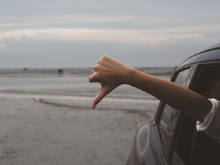 The hand of a girl standing out of the car with thumbs down. Poor driving and inaccurate route...
