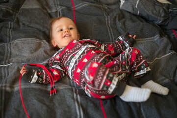 Cute little boy in Christmas pajamas on the bed