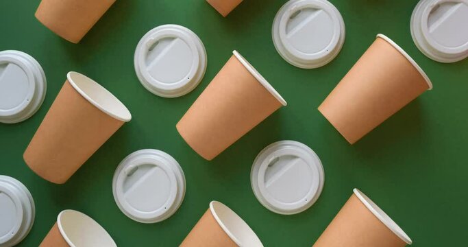 Pattern of craft paper cups and white lids on a green background. Looped 4K stop motion animation
