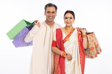 Portrait of a bangali couple in traditional clothing holding shopping bags