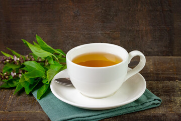 Basil tea in white cup ceramic with green leaf on rustic wooden table. Basil is food and herb for healthy.