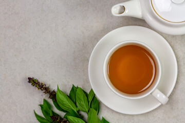 Basil tea in white cup ceramic with green leaf on white background, top view, copy space. Basil is food and herb for healthy.