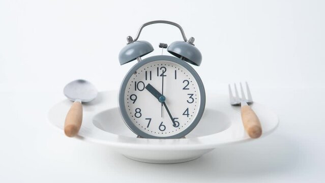 Time to lose weight , intermittent fasting eating control or time to diet concept , alarm clock with dish and spoon  decoration on a white background
