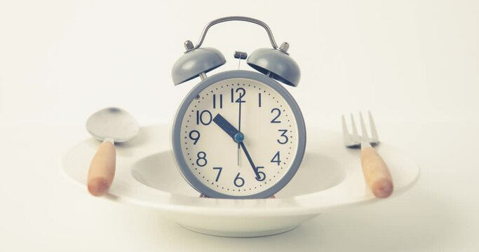 Time to lose weight , intermittent fasting eating control or time to diet concept , alarm clock with dish and spoon  decoration on a white background