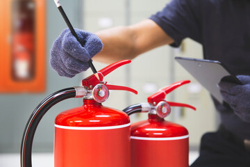 Fire extinguisher has hand engineer inspection checking pressure gauges to prepare fire equipment for protection and prevent in emergency case and safety or rescue and alarm system training concept.