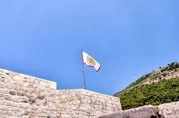 Fototapeta na wymiar Regional flag flying on a tower along the walled city of Dubrovnik 