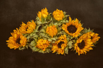 bunch of yellow sunflowers lies on a dark table
