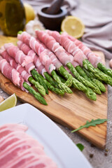 cooking green aspargus covered with bacon at domestic kitchen
