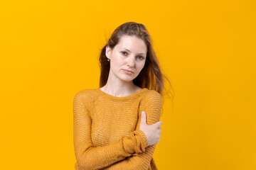 Smiling young female woman in yellow sweater posing isolated on pastel yellow background studio...