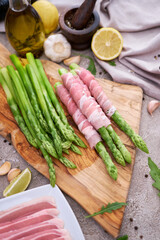 Green organic natural Asparagus on wooden cutting board and slice bacon at kitchen table