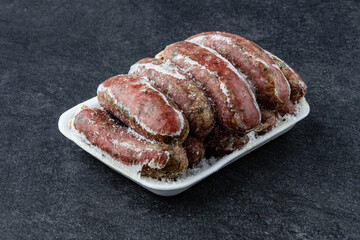Frozen Raw sausage semi-finished products lie on a stone board. The concept of cooking from semi-finished products