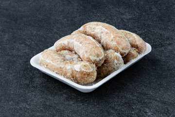 Frozen Raw sausage semi-finished products lie on a stone board. The concept of cooking from semi-finished products