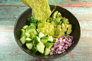 Homemade healthy avocado salad with cucumber, red onion, parsley and avocado lime dressing
